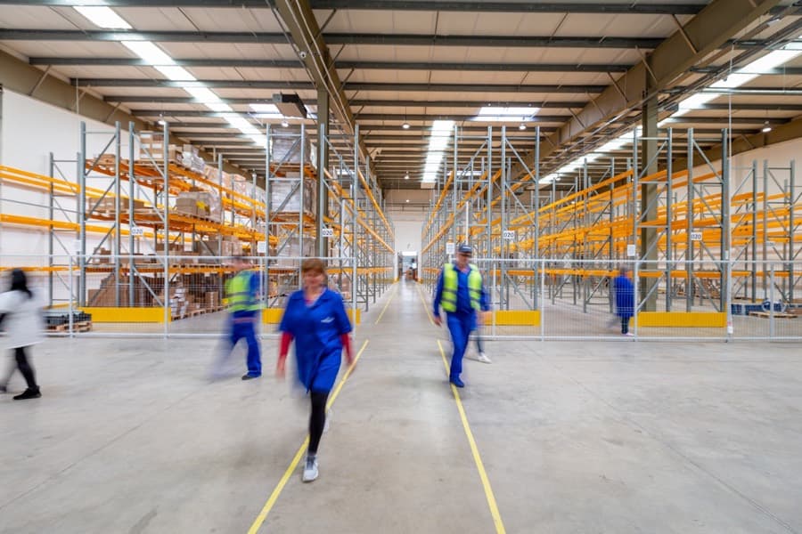 Workers moving through a warehouse aisle
